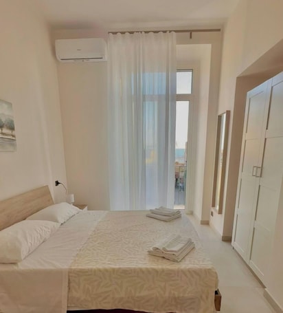A hotel room with a bed, a window with curtains, an air conditioning unit, and a wardrobe.. B&b SunHouse
