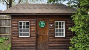 Una cabaña de troncos con una puerta de madera, dos ventanas y un letrero que dice 'Little House in the Big Woods'.