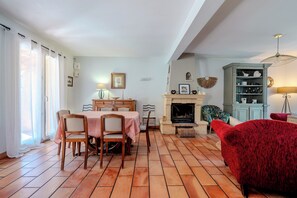 Ein Essbereich mit Tisch und Stühlen, einem Kamin und einem roten Sessel.