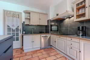 Eine kleine Küche mit Geschirrspüler, Backofen und Kaffeemaschine.