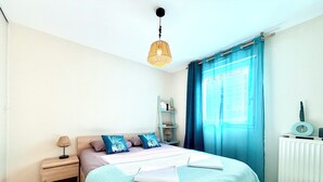 A bedroom with a bed, bedside lamp, and a window with curtains. - T2 parking, prox thermes et centre-ville (Aix-les-Bains)