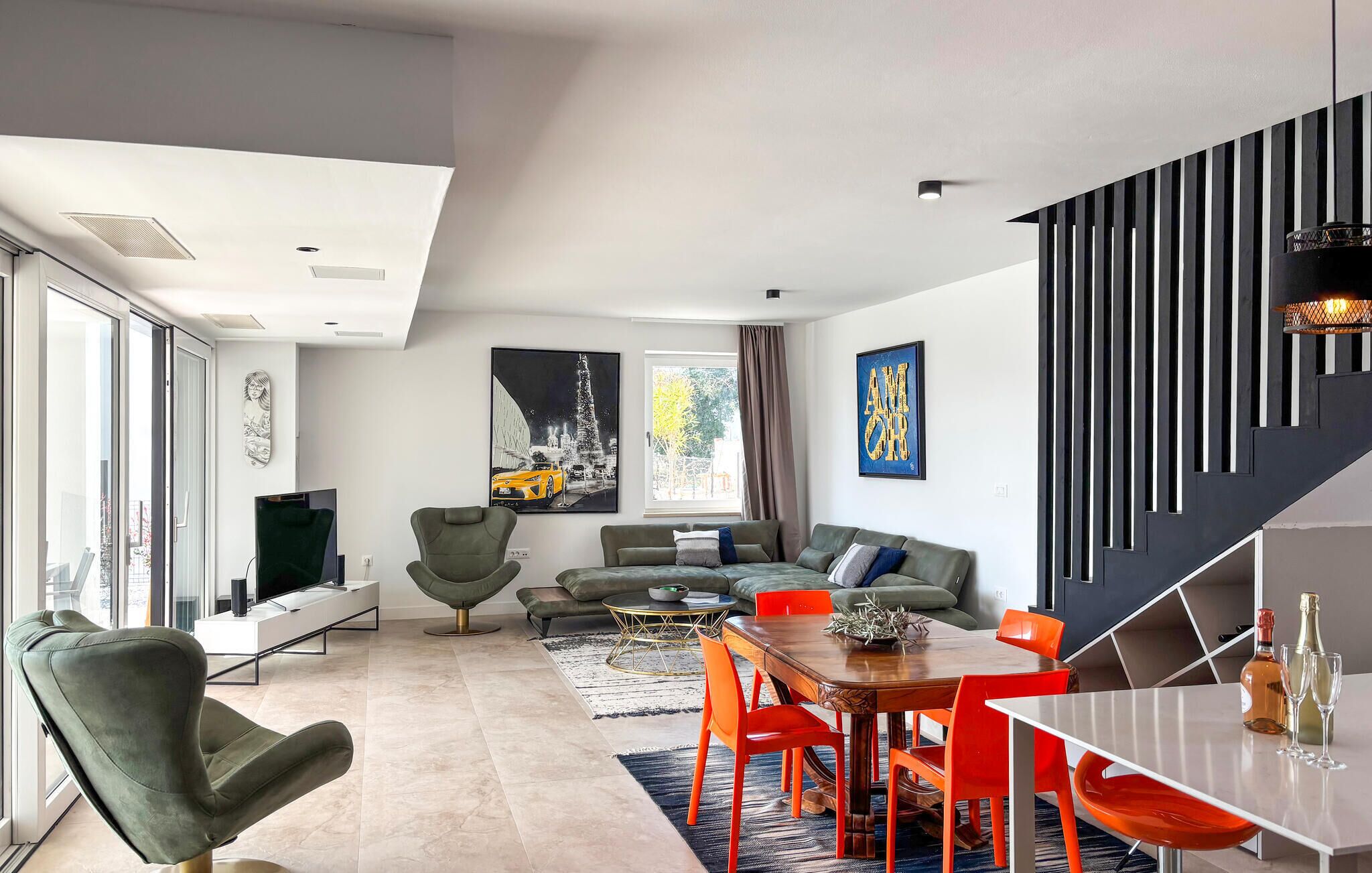 A modern living room with a sofa, chairs, a dining table, and artwork on the walls.