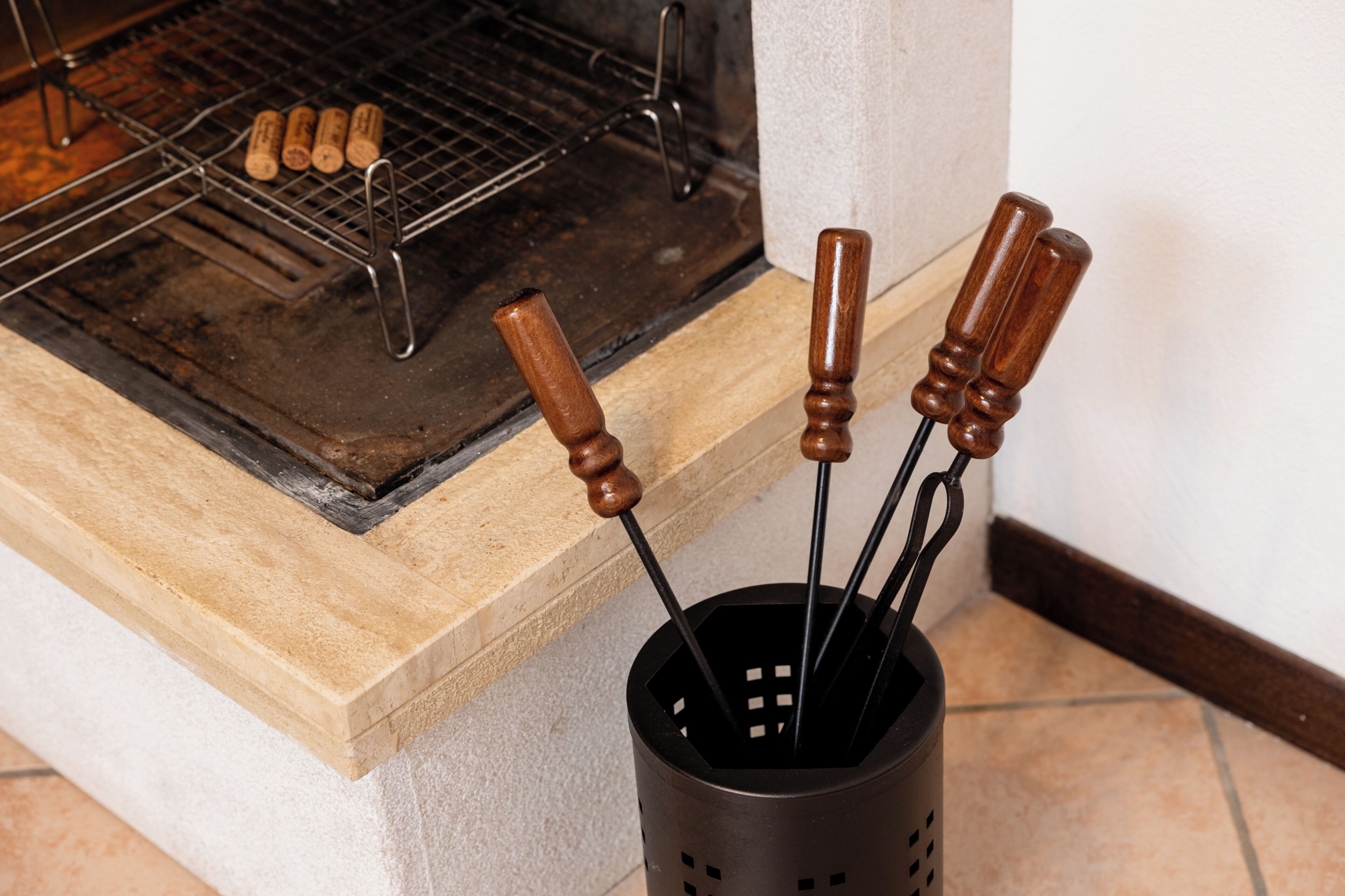 A kitchen with a grill, a wooden cutting board, and a metal utensil holder with handles.