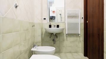 A bathroom with a sink, bidet, and toilet.