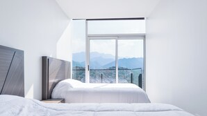 A modern bedroom with a large window, a bed, and a view of mountains. - Micrópolis (Monterrey)