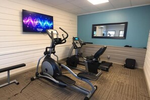 Un gimnasio con una elíptica, una bicicleta estática y una cinta de correr.
