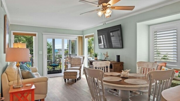 A spacious living room with a ceiling fan, a dining table with chairs, a sofa, and a coffee table. - Pelican's Landing 118- 3BR/2.5BA- Outdoor Pool (Myrtle Beach)