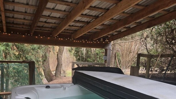 Un jacuzzi debajo de una pérgola de madera con vistas a árboles.