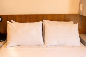 Una cama con ropa de cama blanca y un cabecero de madera.