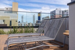Una terraza en la azotea con dos sillones de metal, una mesa de madera y vistas a la ciudad.