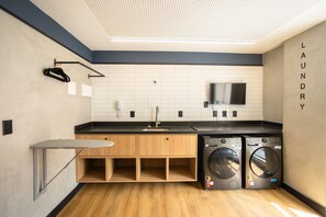 Un lavadero moderno con un lavabo, dos lavadoras y una pequeña mesa.