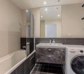 Un baño moderno con bañera, lavamanos y lavadora.