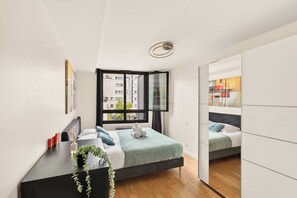 Ein modernes Schlafzimmer mit Bett, Fenster und Spiegel.