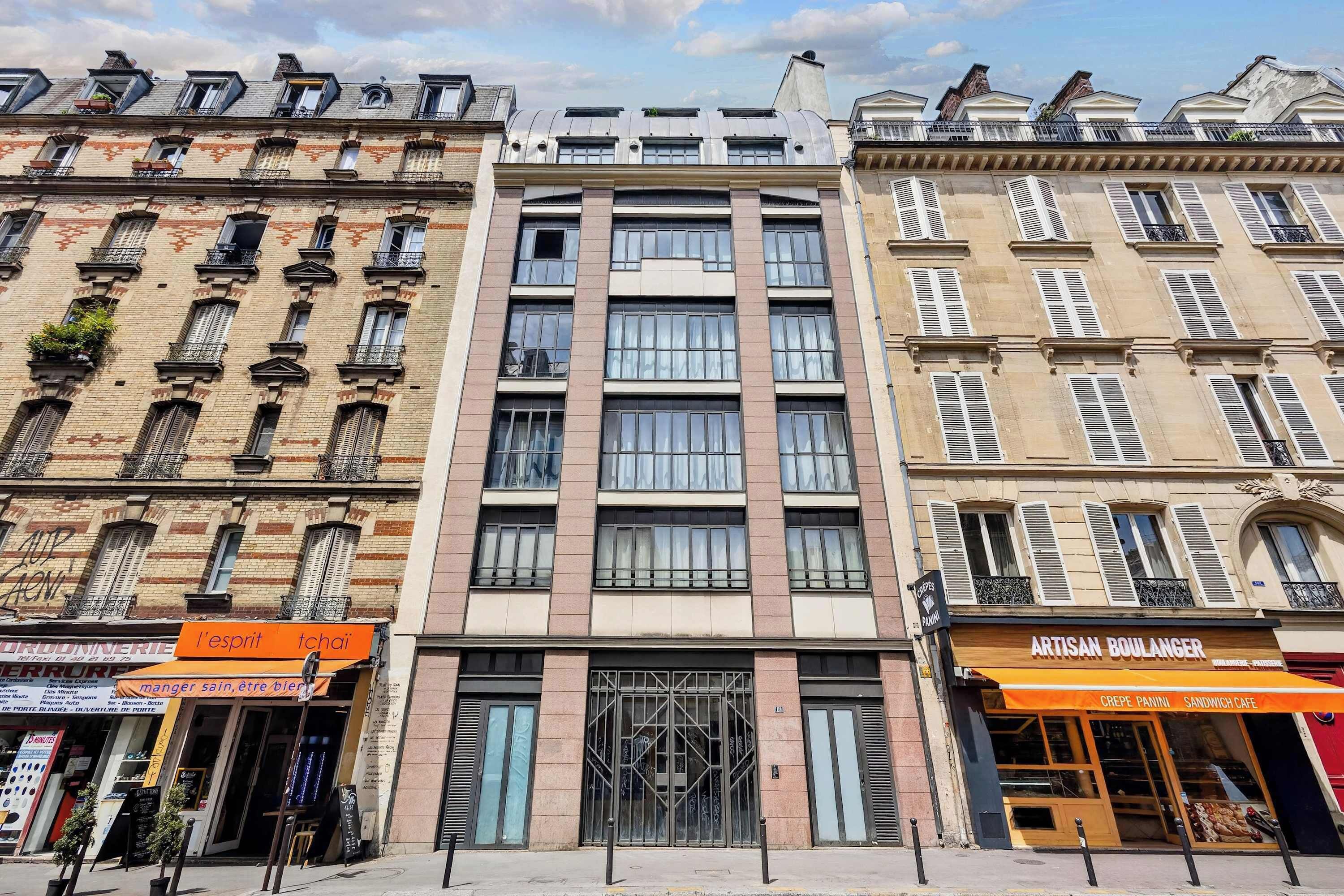 A row of buildings with a mix of architectural styles, including a modern glass facade and traditional brick facades.