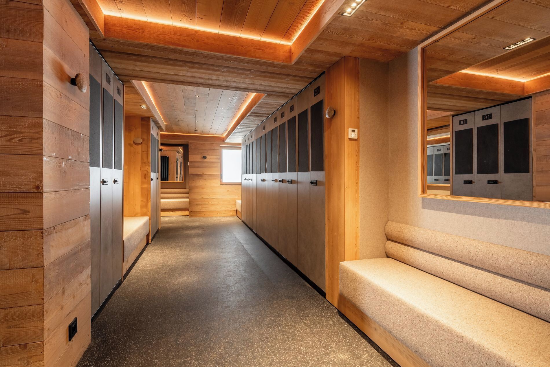 Un couloir aux murs en bois, avec des bancs et des casiers.