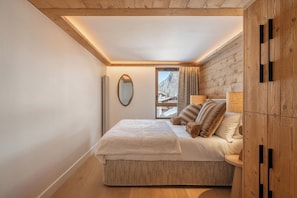 Ein Schlafzimmer mit einem Bett, einem Spiegel, einem Fenster mit Aussicht und Holzwänden.