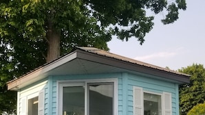 Une petite maison bleu clair, dotée d’une porte-fenêtre coulissante et de volets blancs.