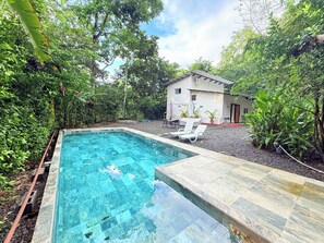 A rectangular pool with clear water, surrounded by a stone deck and lush greenery. - Modern 2 Bedroom Scenic Retreat w/ Pool and Fitness Studio (Paraiso)