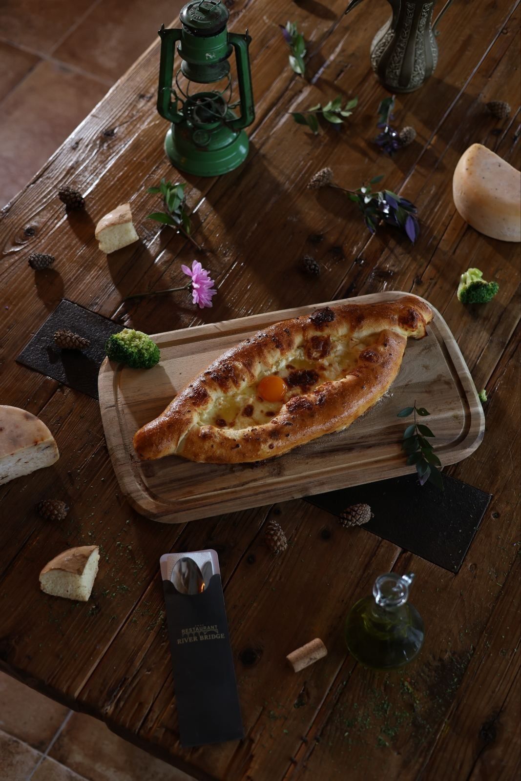 Une table en bois rustique, sur laquelle on trouve un sandwich au fromage grillé, une bouteille et un tire-bouchon.