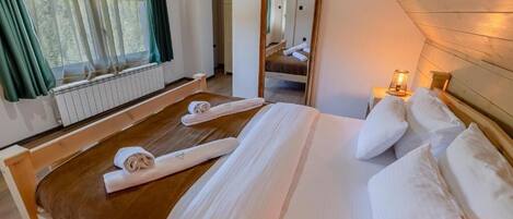 Un dormitorio con una cama de madera, una ventana con cortinas, un radiador y una mesita de noche con una lámpara.