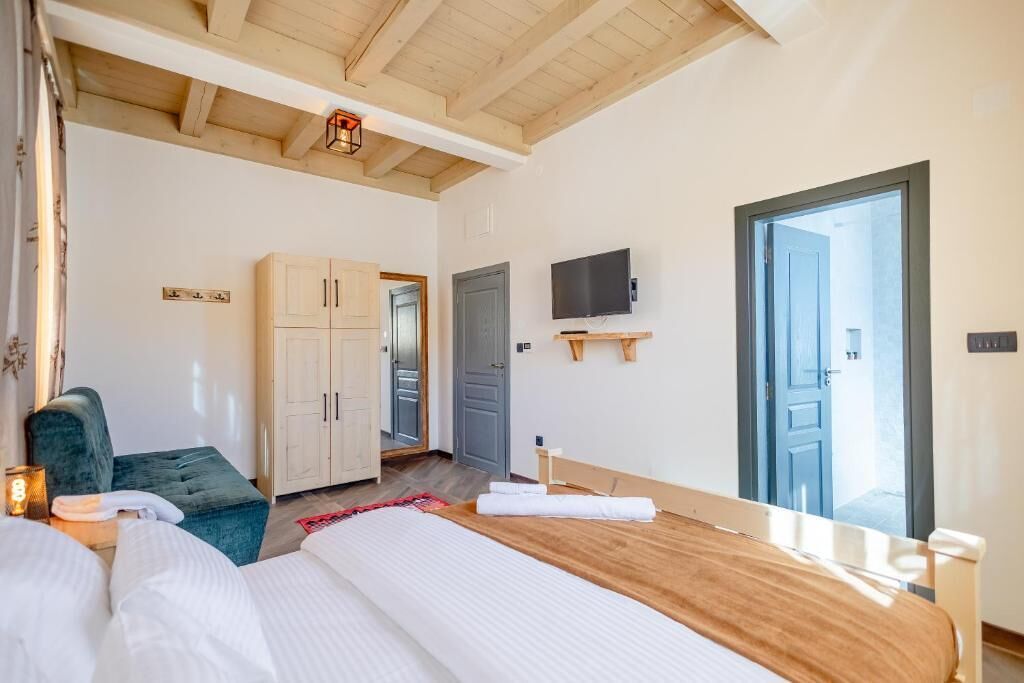 Quarto com teto de madeira, uma cama, televisão e guarda-roupa.