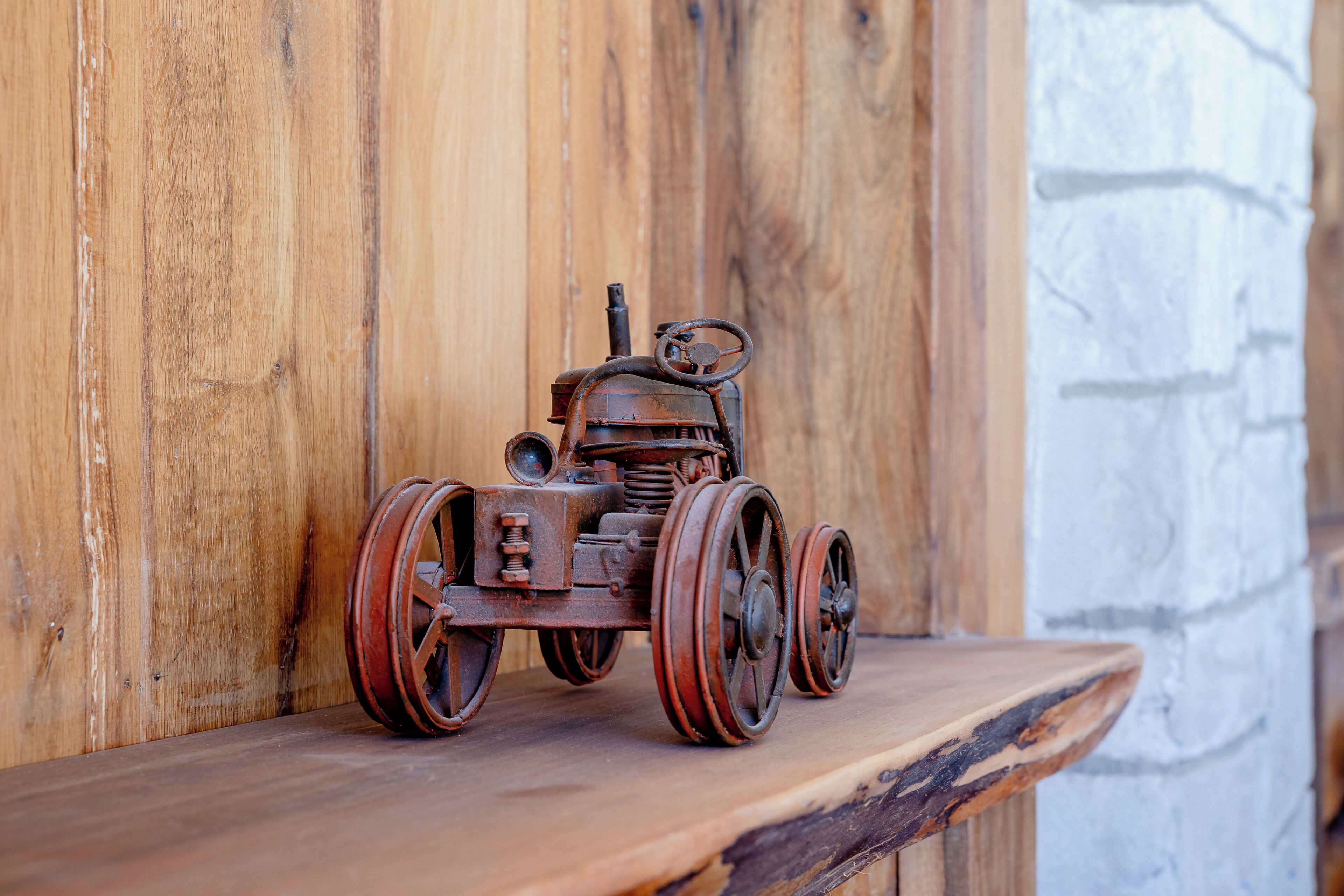 Une étagère en bois rustique sur laquelle est posé un modèle de tracteur ancien.