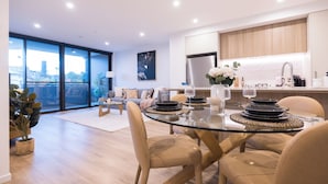 Uma sala de estar moderna com uma mesa de jantar de vidro, sofá e vista da cidade.