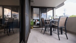 Varanda moderna com área de refeições, uma cama e vista para a cidade.