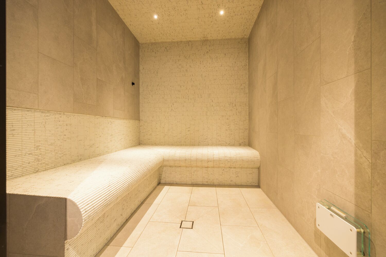 Una stanza spa con una panca, pareti piastrellate e una lampada a soffitto.