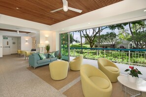 A modern hotel lobby with a large window, a wooden ceiling, and a seating area with yellow chairs. - Waikiki Shore 1402 Ocean View 2 Bedroom (Honolulu)