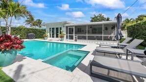 A modern house with a swimming pool, outdoor seating, and a covered patio area. - Remodeled Mid-century home with pool, hot tub & EV charger (Wilton Manors)