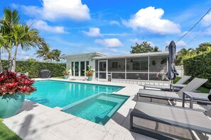 A modern house with a swimming pool, outdoor seating, and a covered patio area. - Remodeled Mid-century home with pool, hot tub & EV charger (Wilton Manors)