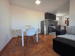 A compact living space with a kitchenette, a dining area with a white table and chairs, and a sofa. - Elena's Corner (Funchal)