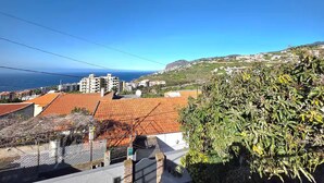 A residential area with terracotta-roofed buildings, a clear blue sky, and a distant view of the sea. - Elena's corner (Funchal)