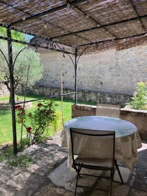 Un espacio de estar al aire libre cubierto con una mesa, una silla, un muro de piedra y una estructura de pérgola.