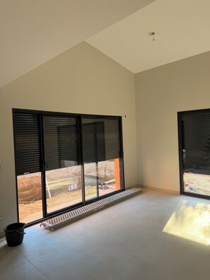 Una habitación con grandes puertas correderas de vidrio, un respiradero metálico y suelo de baldosas.