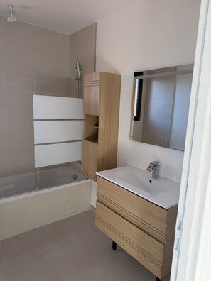 Un baño moderno con una bañera, un tocador de madera, un lavabo y un espejo.