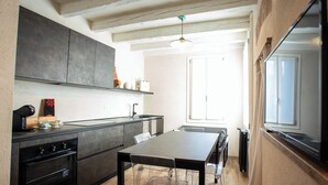 A modern kitchen with dark cabinets, a wooden table, and a large window.