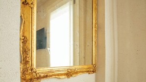 A gold-framed mirror with a stone base on a wall.