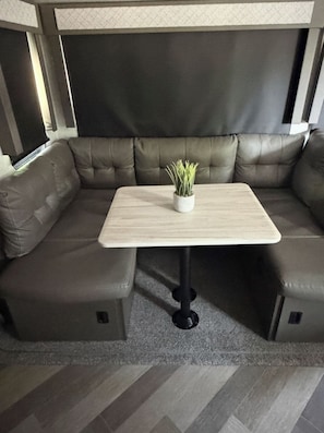 Un canapé d’angle avec une petite table au centre, une plante en pot posée sur la table et un tapis à motifs.