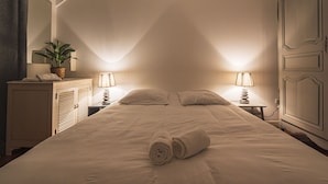 A hotel room with a large bed, two bedside lamps, a potted plant, and a dresser. - Unusual bubbles (Reims)