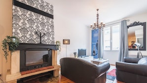 A living room with a fireplace, two sofas, a TV, and a chandelier. - Unusual bubbles (Reims)