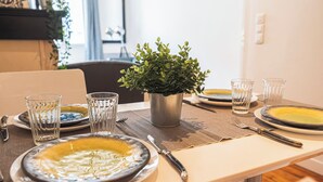 A dining table set with plates, glasses, and cutlery, a potted plant, and a window in the background. - Unusual bubbles (Reims)