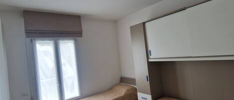 Um apartamento pequeno, com um quarto, uma cama, uma escrivaninha e um guarda-roupa.