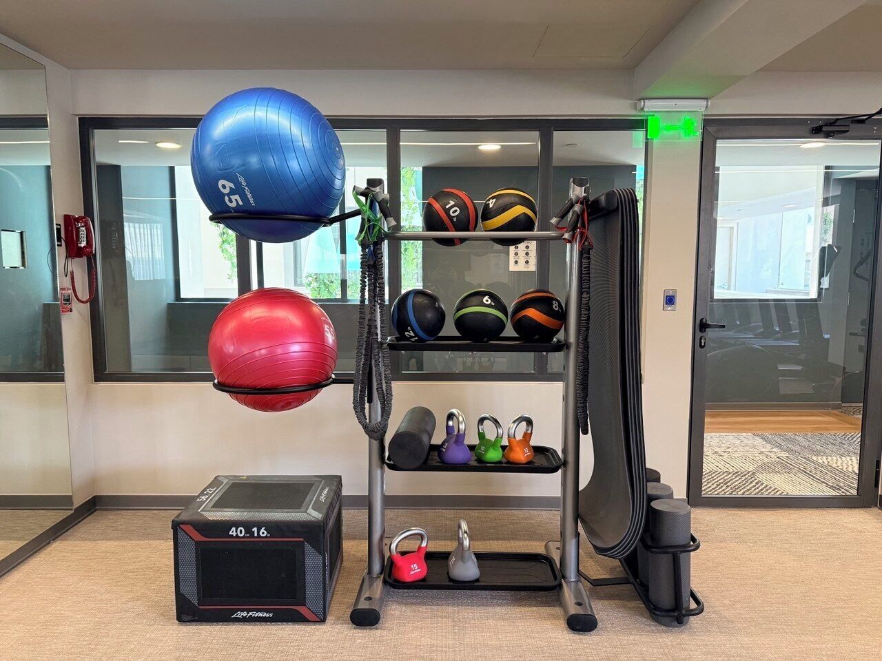 A gym with exercise equipment, including kettlebells, medicine balls, and a weight bench.