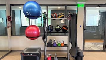 A gym with exercise equipment, including kettlebells, medicine balls, and a weight bench.