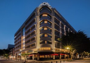 Un hotel de varios pisos con un diseño moderno, que presenta un llamativo letrero con la palabra 'moto' en la parte superior.