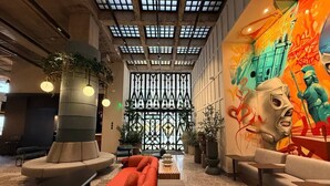 Un vestíbulo moderno con una zona de estar central, una columna decorativa y un mural grande en la pared.