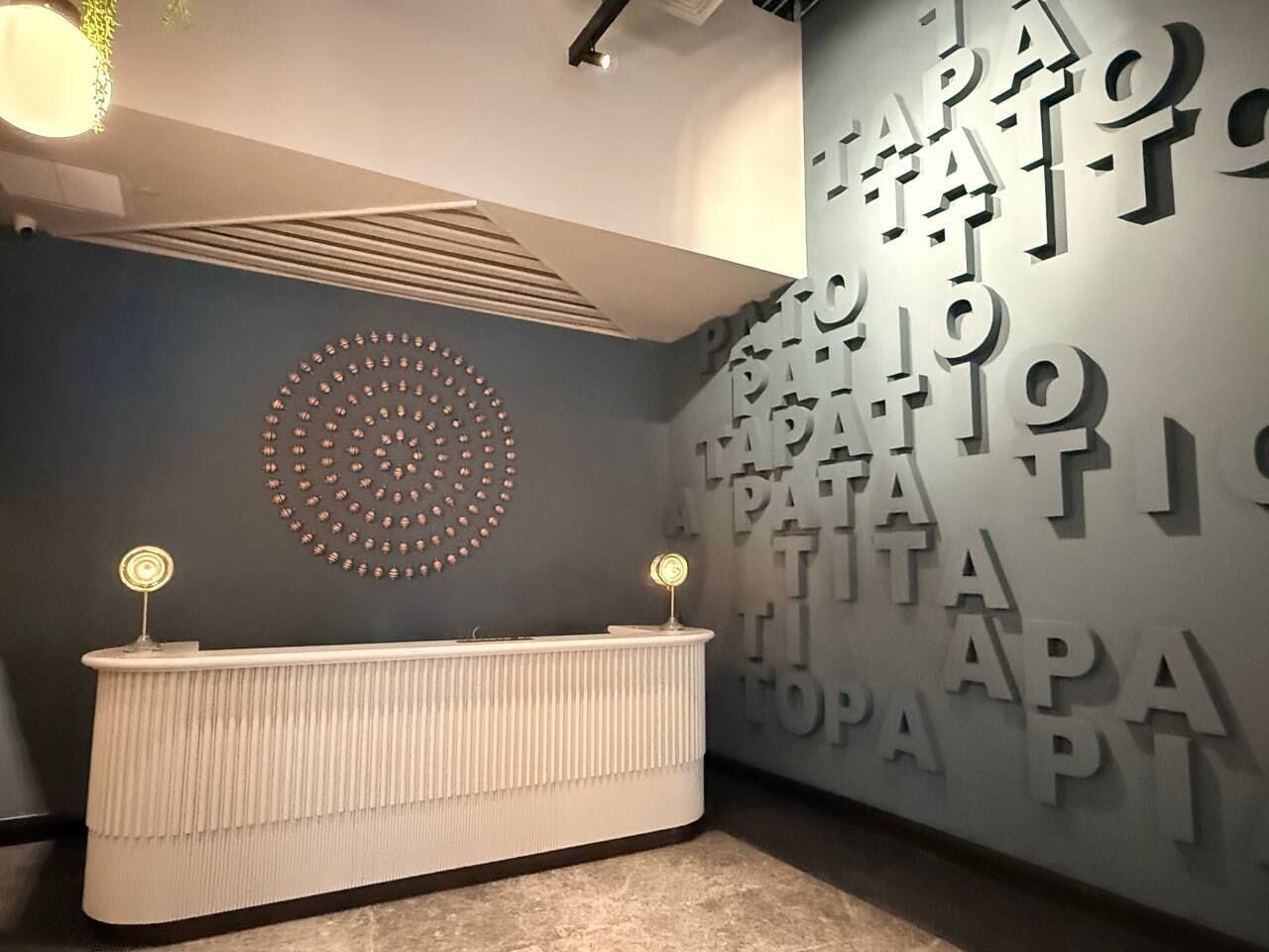 A reception area with a modern design, featuring a white reception desk and a wall with large letters.