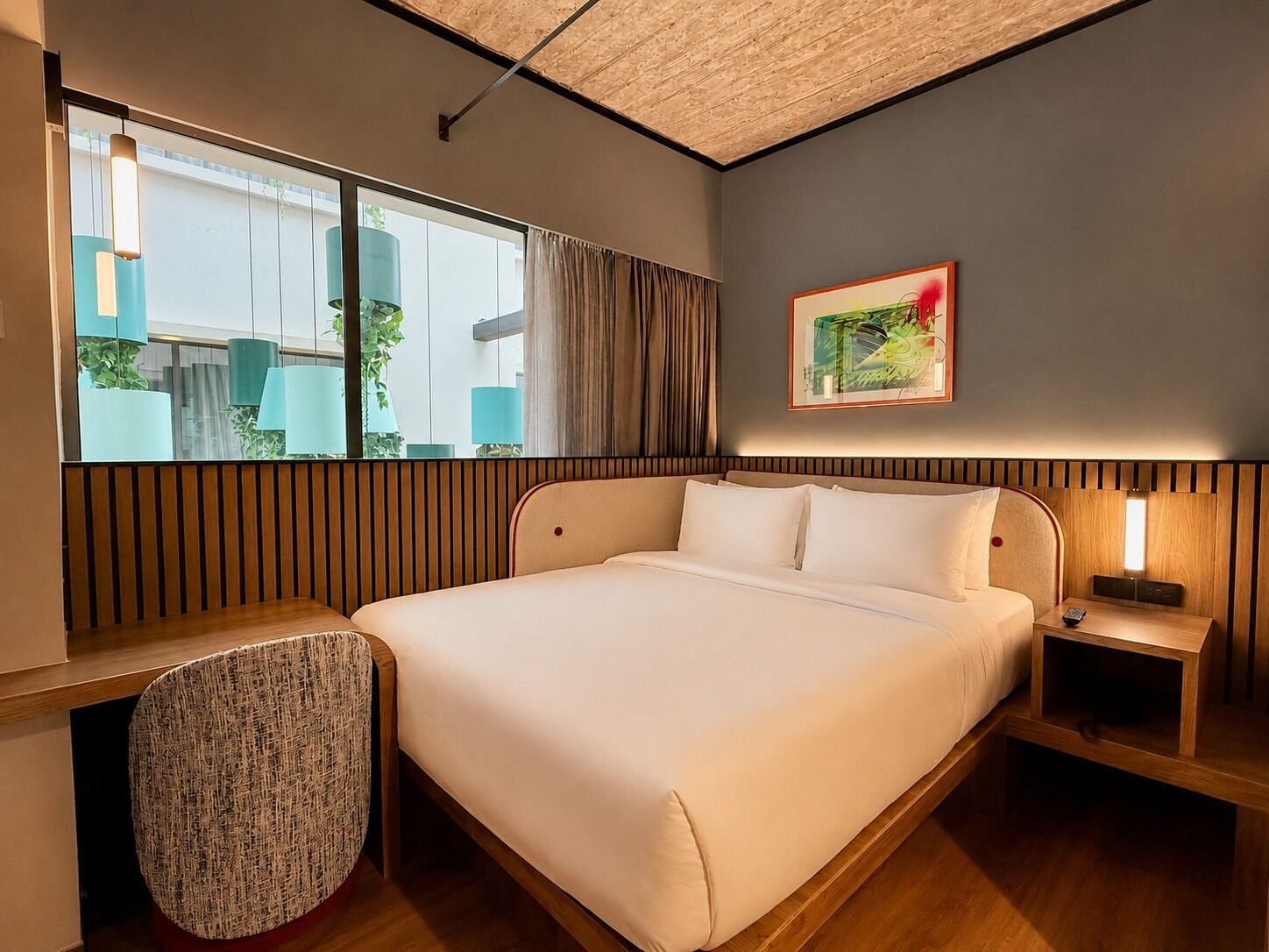 Une chambre d’hôtel moderne avec un grand lit, une table de chevet, une chaise et une fenêtre avec des rideaux.